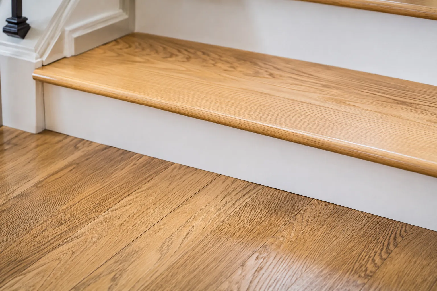 Close-up of a refinished oak stair tread meeting the hardwood floor